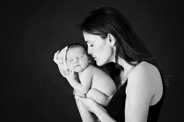 Madre baciare e abbracciare il figlio neonato su sfondo grigio, tende — Foto Stock