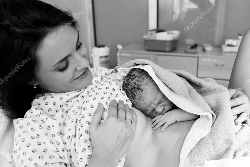 Happy mom, having her baby skin to skin first seconds after birt