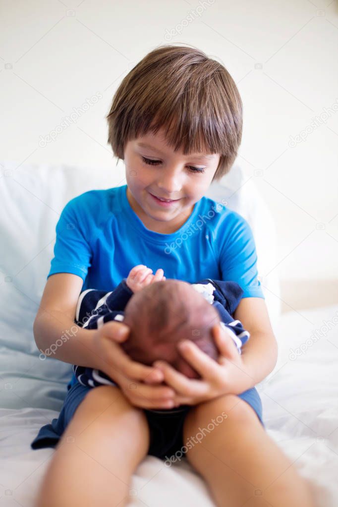 Cute boy, brother, meeting for the first time his new baby broth