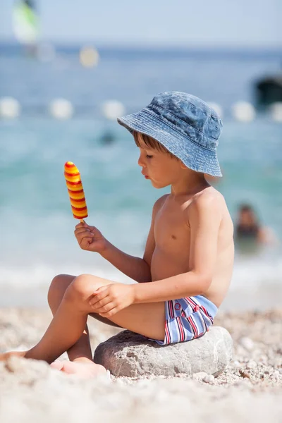 Lief kindje, jongen, eten van ijs op het strand — Stockfoto