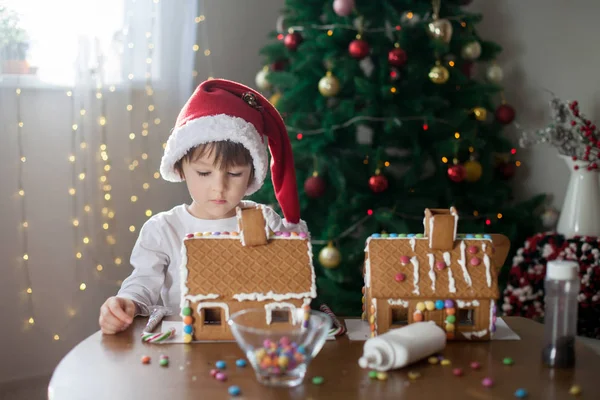 Niedlicher kleiner Junge, der Lebkuchenhaus für Weihnachten backt — Stockfoto