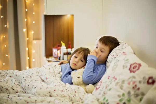 Två söta sjuka barn, pojkar, stanna i sängen med feber — Stockfoto