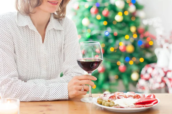 Mujer joven, bebiendo vino y merienda en casa en Navidad —  Fotos de Stock