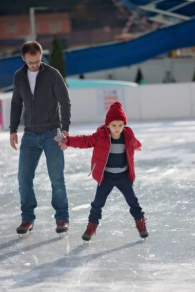 Happy excited little boy and his young father learning ice-skati — Stock Photo, Image