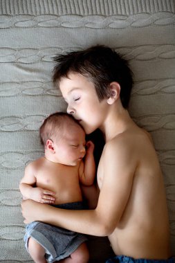 Beautiful boy, hugging with tenderness and care his newborn baby clipart