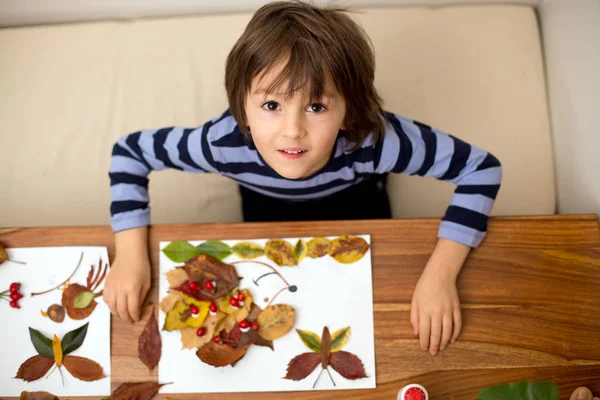 Γλυκό παιδί, αγόρι, εφαρμόζοντας φύλλα χρησιμοποιώντας κόλλα ενώ κάνει Τεχνών ενός — Φωτογραφία Αρχείου