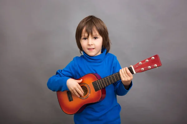 Vorschulkind, kleine Gitarre spielend, isoliertes Bild — Stockfoto