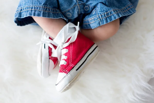 Zapatillas de deporte rojas de moda en los pequeños pies de los niños recién nacidos —  Fotos de Stock