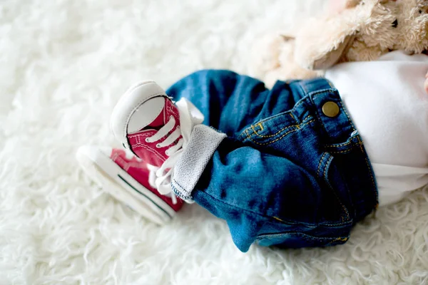 小さな生まれたばかりの赤ちゃんの男の子の足のファッショナブルな赤いスニーカー — ストック写真