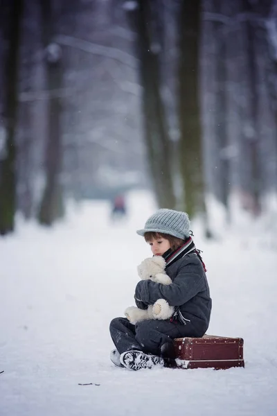 Verdrietig kind, jongen, wandelen in een bos met oude koffer en teddy — Stockfoto