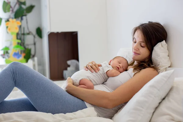 Joven madre acostada en la cama con su bebé recién nacido — Foto de Stock