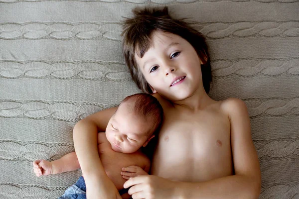 Menino bonito, abraçando com ternura e cuidar de seu bebê recém-nascido — Fotografia de Stock