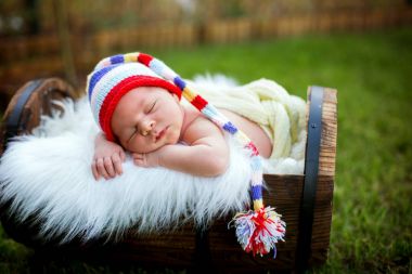 Little sweet newborn baby boy, sleeping in crate with knitted pa clipart
