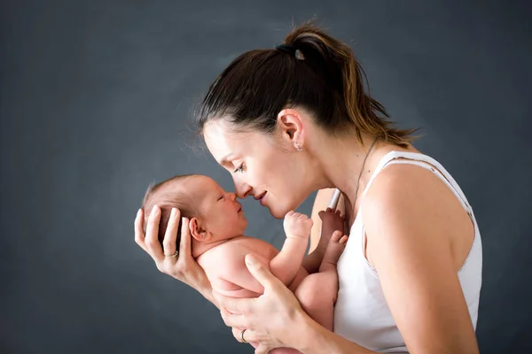 Joven madre, besando y abrazando a su bebé recién nacido — Foto de Stock