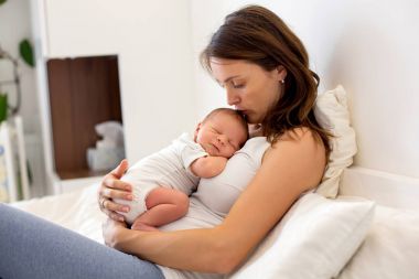 Genç anne onun yeni doğan bebek çocuk ile yatakta yalan