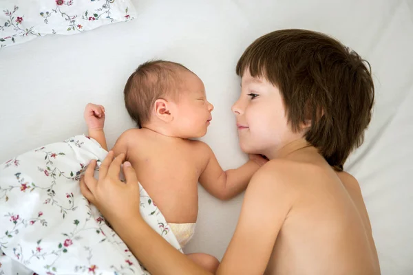 Menino bonito, abraçando com ternura e cuidar de seu bebê recém-nascido — Fotografia de Stock