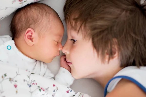 Bbeautiful pojke, kramas med ömhet och omsorg hans nyfödda bab — Stockfoto