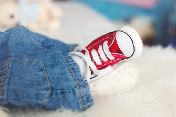 Fashionable red sneakers on little newborn baby boys feet — Stock Photo, Image