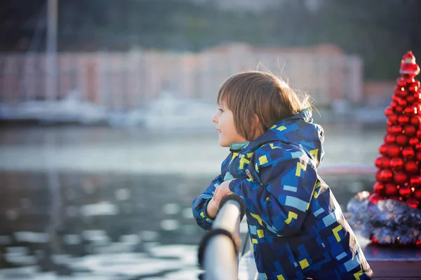 Симпатичный счастливый ребенок, путешествующий на лодке по озеру во время Рождества — стоковое фото