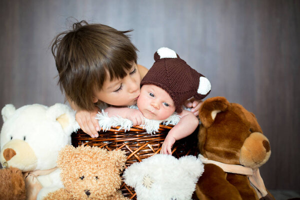 Cute newborn baby boy in basket with teddy bear hat, looking at 
