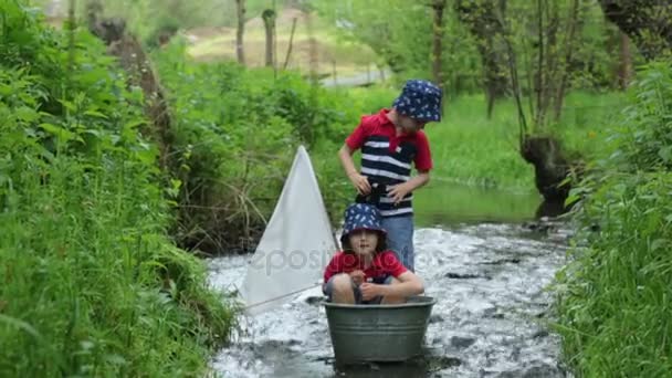 Sevimli çocuk, erkek kardeşler, tekne ve yelken ve kürek küçük bir nehir üzerinde ördekler ile oynarken. Çocuklar eğleniyor, çocukluk mutluluk kavramı — Stok video