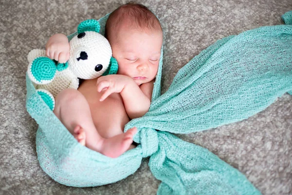 Sover nyfödda pojke i sängen, kramas stickad leksak — Stockfoto