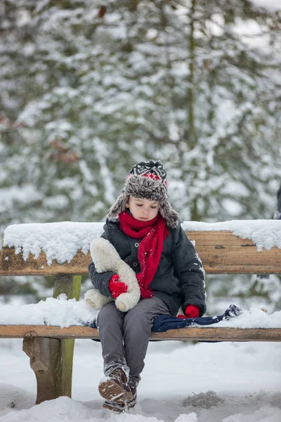 Dos niños, hermanos varones, sentados en un banco en el parque, invierno — Foto de Stock