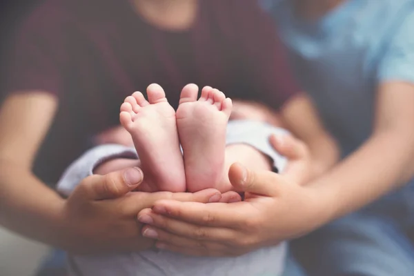 Pequeño bebé pies en hermanos manos — Foto de Stock