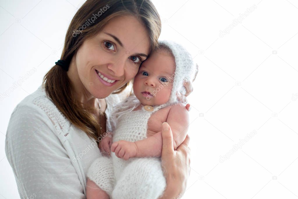 Young mother, kissing her newborn baby boy at home, mom and baby