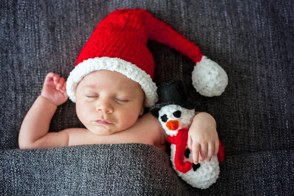 Little sleeping newborn baby boy, wearing Santa hat and holding — Stock Photo, Image