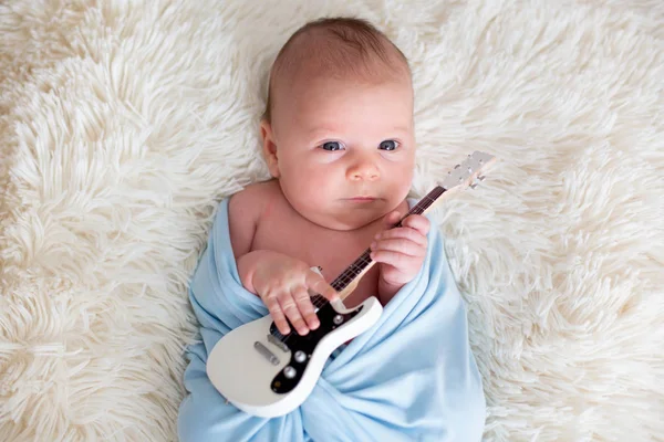 Newborn baby boy, holding a little guitarand smiling — Stock Photo, Image