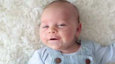 Mutlu bir şekilde gülümseyerek, yatakta uzanarak kameraya bakarak şirin yeni doğmuş bebek,