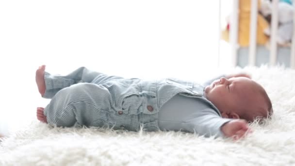 Lindo bebé recién nacido, mirando a la cámara, sonriendo alegremente, acostado en la cama — Vídeo de stock