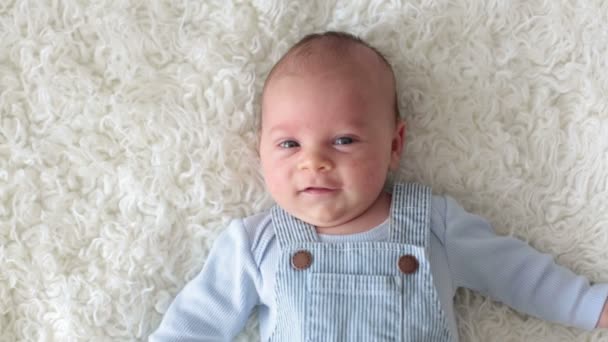 Lindo bebé recién nacido, mirando a la cámara, sonriendo alegremente, acostado en la cama — Vídeos de Stock