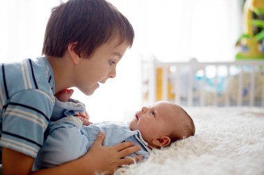 Güzel çocuk, hassasiyet ile sarılma ve onun yeni doğan Bebek Bakımı