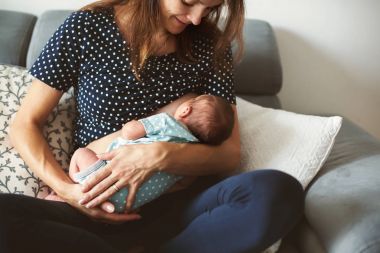 Genç breastfeeds bebeği kucağında gözaltında, anne.