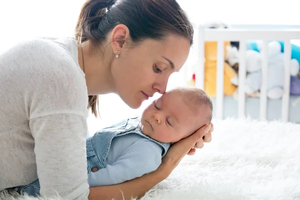 Щаслива мати, розмовляє зі своїм новонародженим сином, погладжує і цілує h — стокове фото