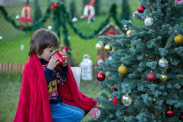 Niedlicher kleiner Junge, Weihnachtsbaum schmücken, im Freien — Stockfoto