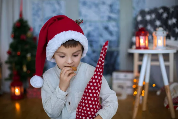 Schattig preschool kind, jongen, het lezen van een boek en het eten van cookies op — Stockfoto