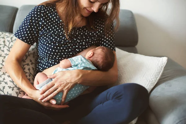 Joven madre amamanta a su bebé, sosteniéndolo en sus brazos — Foto de Stock