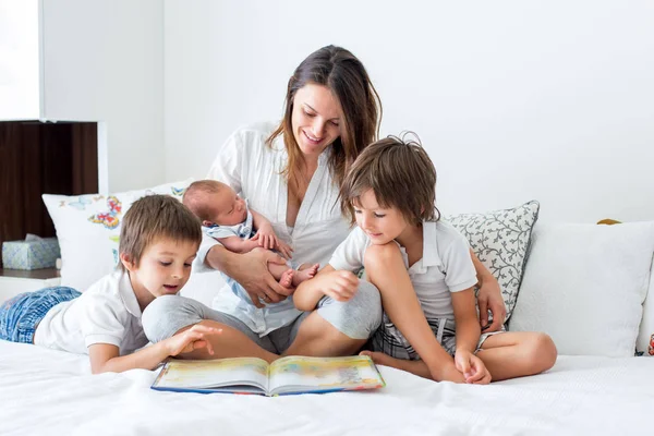 Молодая мать, читать книгу ее трех детей, мальчики, в быть — стоковое фото