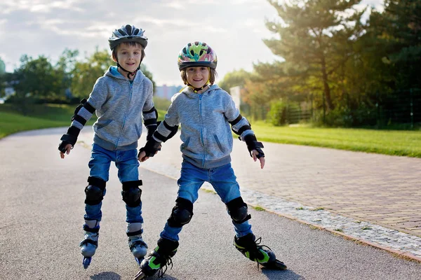 Ung söt förskolebarn, pojke bröder, skridskor i parken — Stockfoto