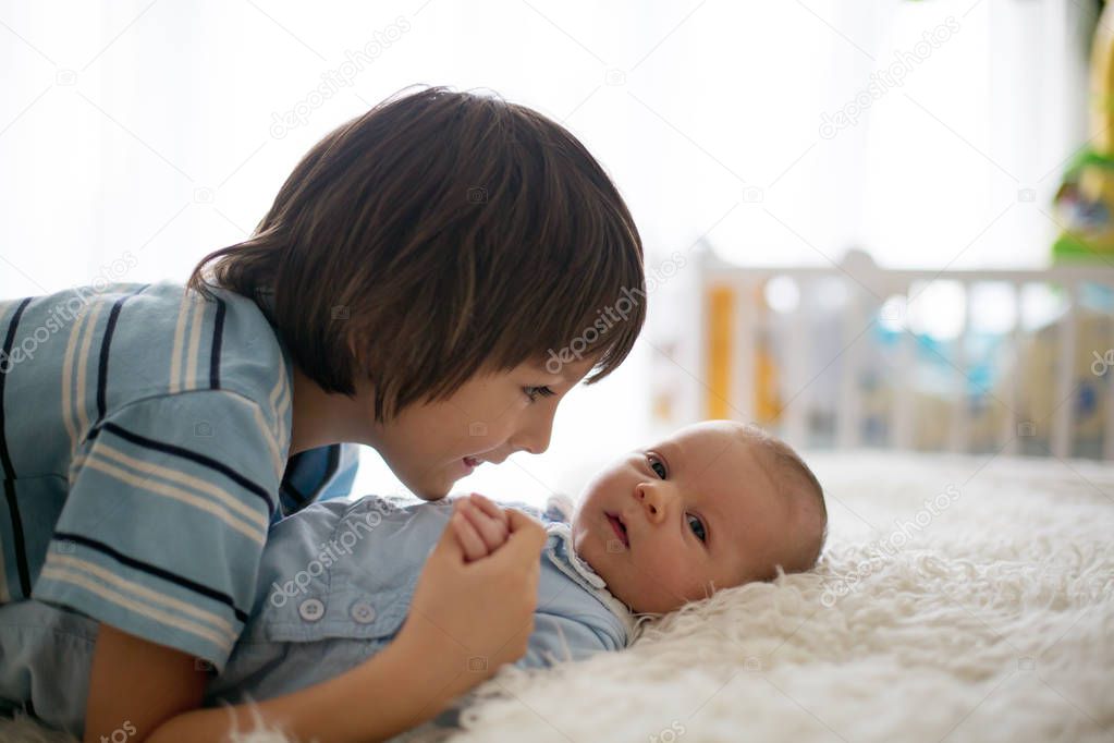 Beautiful boy, hugging with tenderness and care his newborn baby