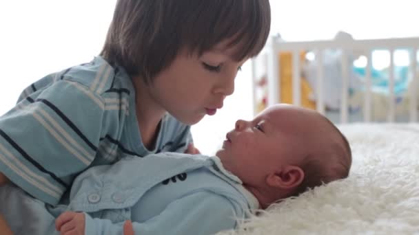 Beau garçon, embrassant avec tendresse et soin son petit frère nouveau-né à la maison. Famille amour bonheur concept — Video