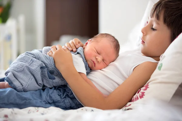 Menino bonito, abraçando com ternura e cuidar de seu bebê recém-nascido — Fotografia de Stock