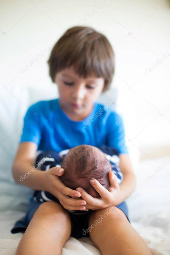 Cute boy, brother, meeting for the first time his new baby broth
