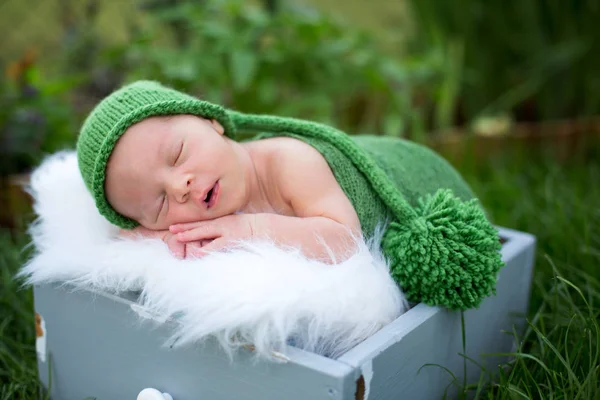 Kleine zoete pasgeboren babyjongen, slapen in een krat met wrap en h — Stockfoto