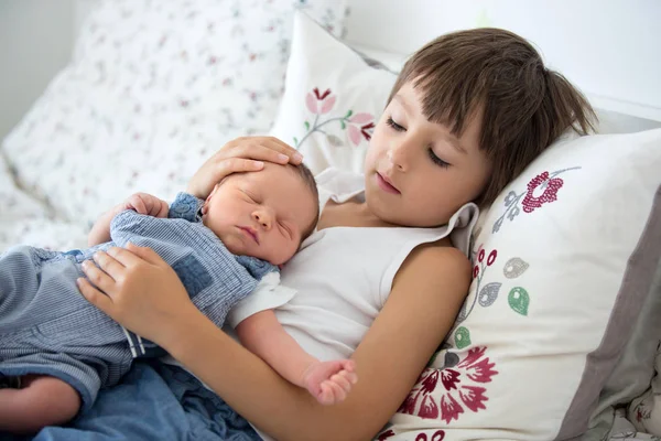 Hermoso niño, abrazando con ternura y cuidar a su bebé recién nacido — Foto de Stock
