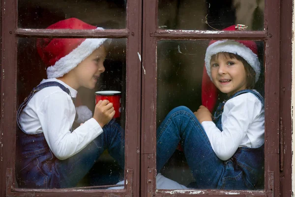 Dois meninos bonitos, irmãos, olhando através de uma janela, esperando por S — Fotografia de Stock