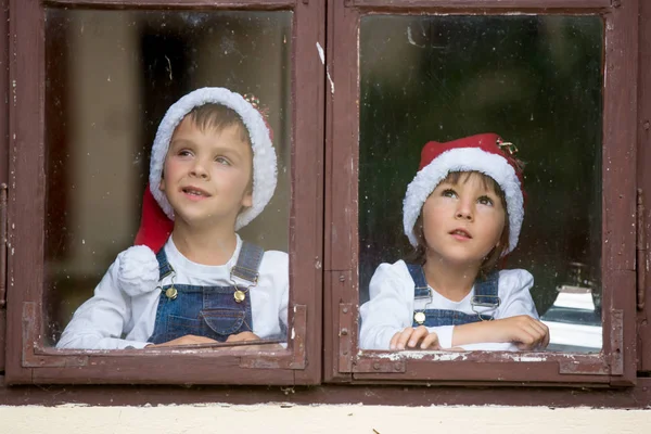 Due ragazzi carini, fratelli, che guardano attraverso una finestra, aspettando S — Foto Stock